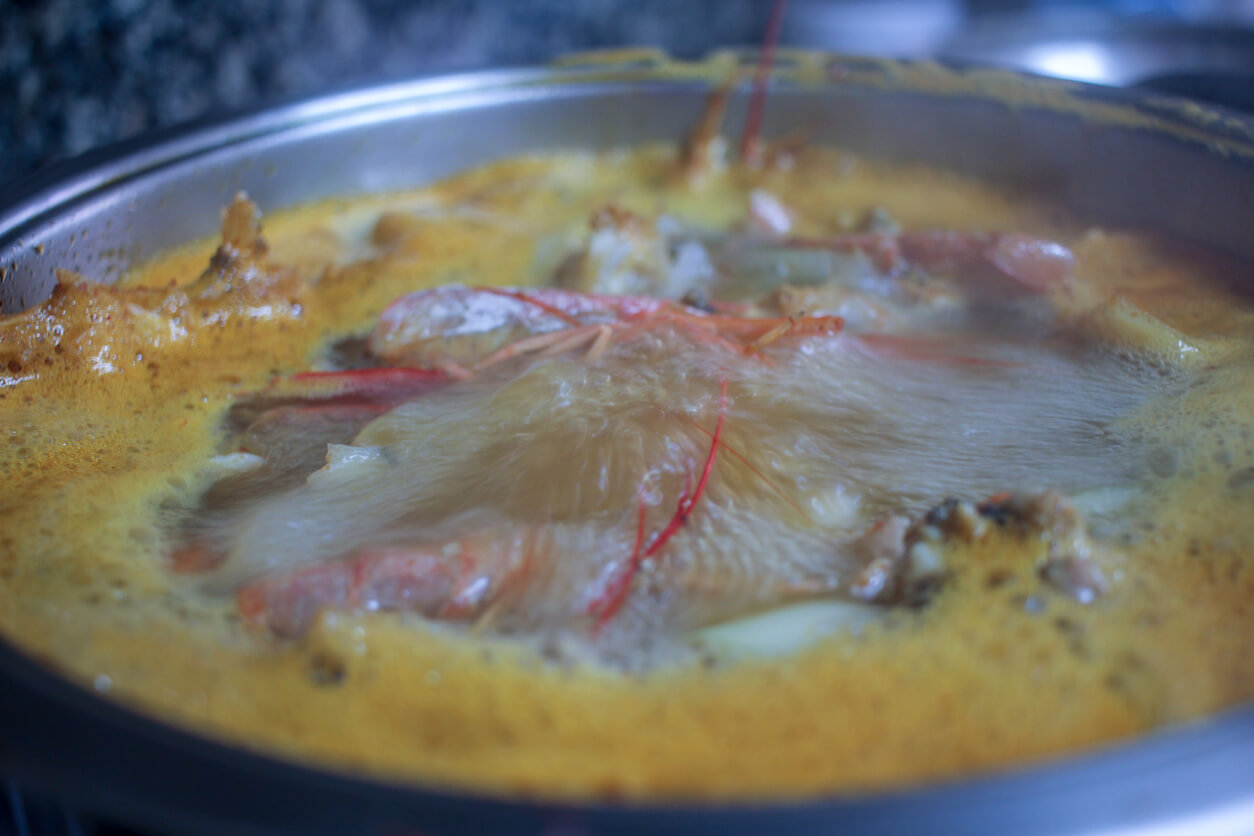 A bubbling pot unveils the creation of a fish broth infused with succulent shrimp.