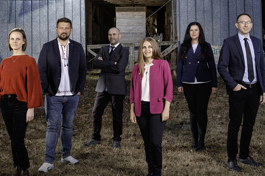 From left, CAES Associate Professor Abigail Borron and Fulbright Romanian-American Foundation Scholars Mihai Suteu, Daniyar Memedemin, Alina Zaharia, Andreea Ona and Daniel Chiciudean stand in front of an image of the Romanian flag projected onto a barn at UGArden.